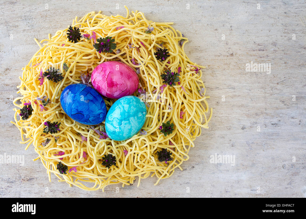 Konzept und Idee Ostereier in einem Nest aus Eiernudeln auf einem Leuchttisch farbigen Holz. Kopie Raum Platz für text Stockfoto