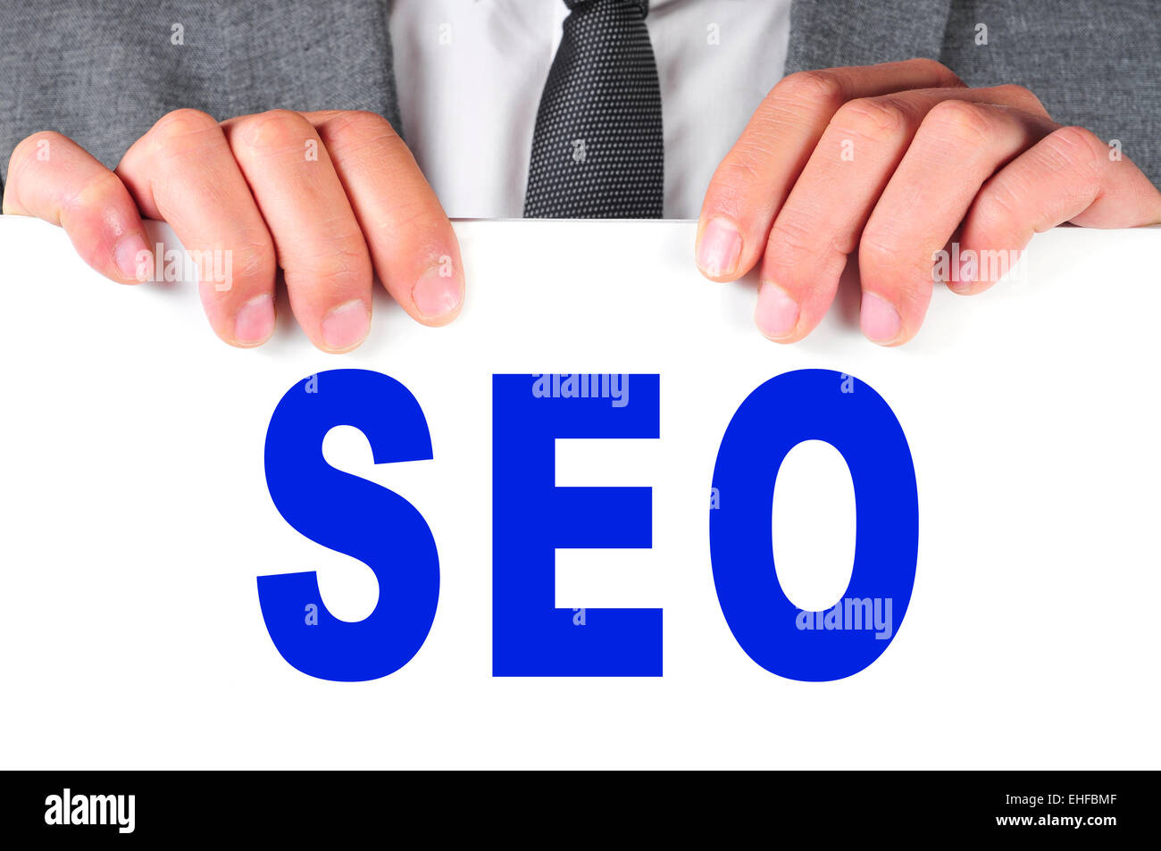 ein Mann in einem Anzug hält ein Schild mit dem Wort SEO, Abkürzung für Search Engine Optimization, geschrieben Stockfoto