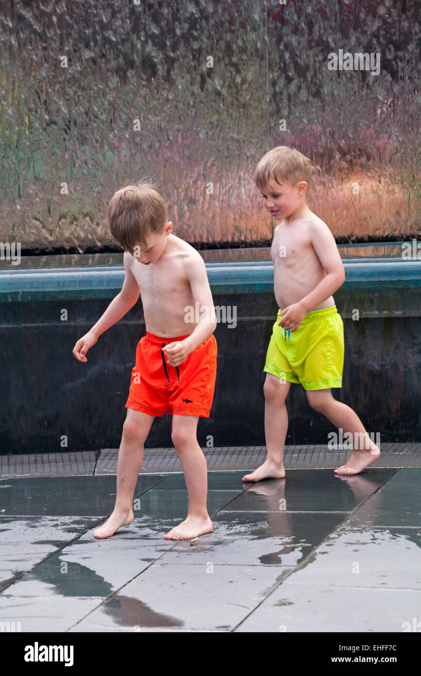 genießen das Wasser - Kinder spielen im Wasserbrunnen im Millenium Square, Harbourside, Bristol im Mai Stockfoto