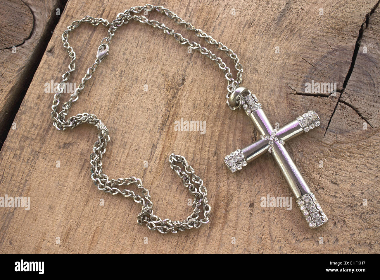 Silberne christliche Kreuz mit kleinen Diamanten auf hölzernen Hintergrund Stockfoto