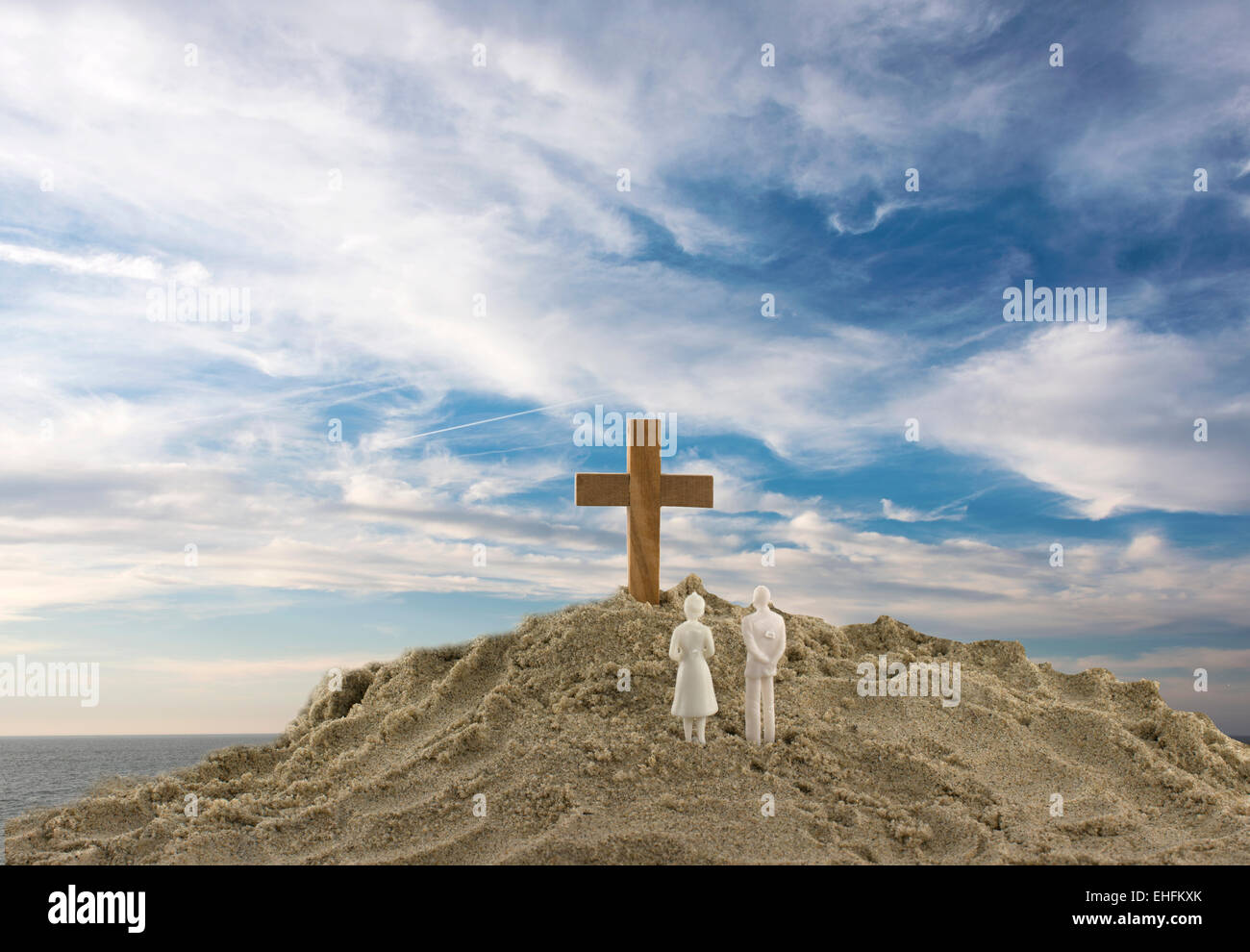 Spielzeug-paar auf der Suche auf das Heilige Holzkreuz auf Sand Berg Stockfoto