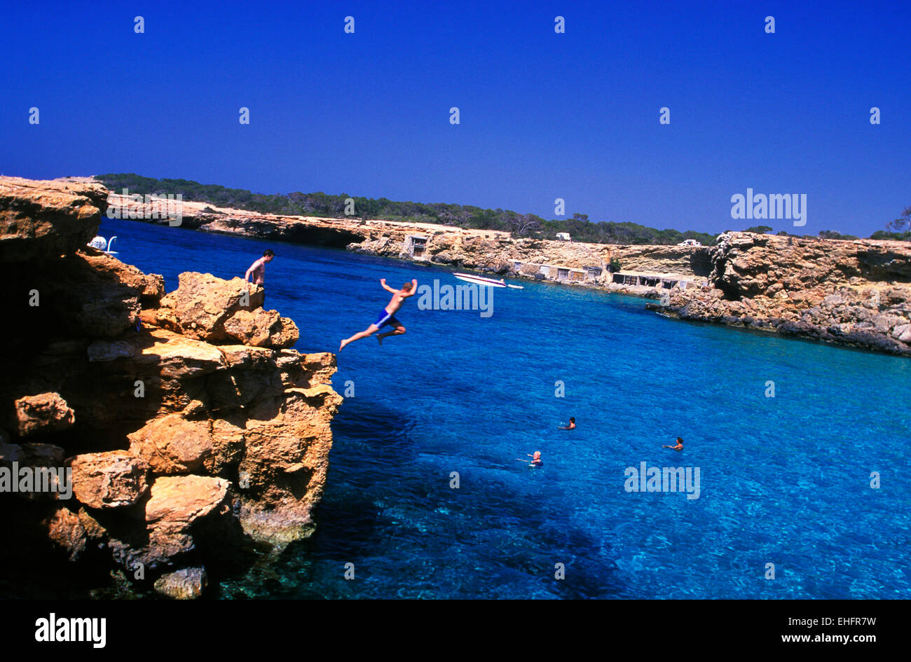 Mann springt von Klippe am Strand von Cala Conte auf Ibiza. Stockfoto