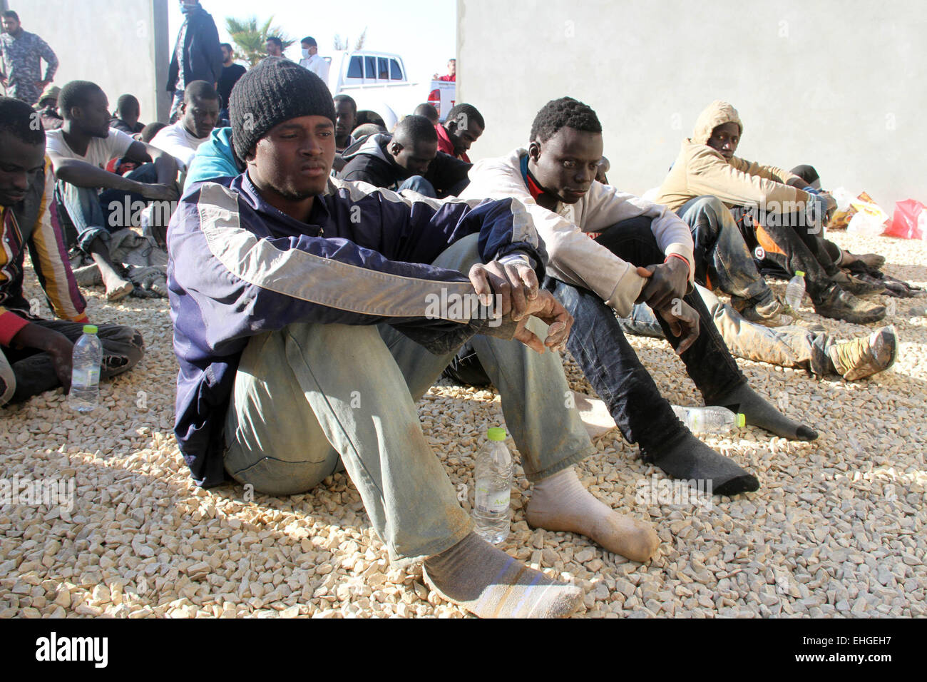 (150313)--Tripolis, März 13, 2015(Xinhua)--illegale Einwanderer sitzen in einem Hof, bewacht von der libyschen Polizei in Tripolis, Libyen, am 13. März 2015. Libyen ist seit langem ein Durchgangsort für Migranten, die darauf abzielen, Malta, Italien und anderswo in Europa zu erreichen. (Xinhua/Hamza-Türkei) Stockfoto