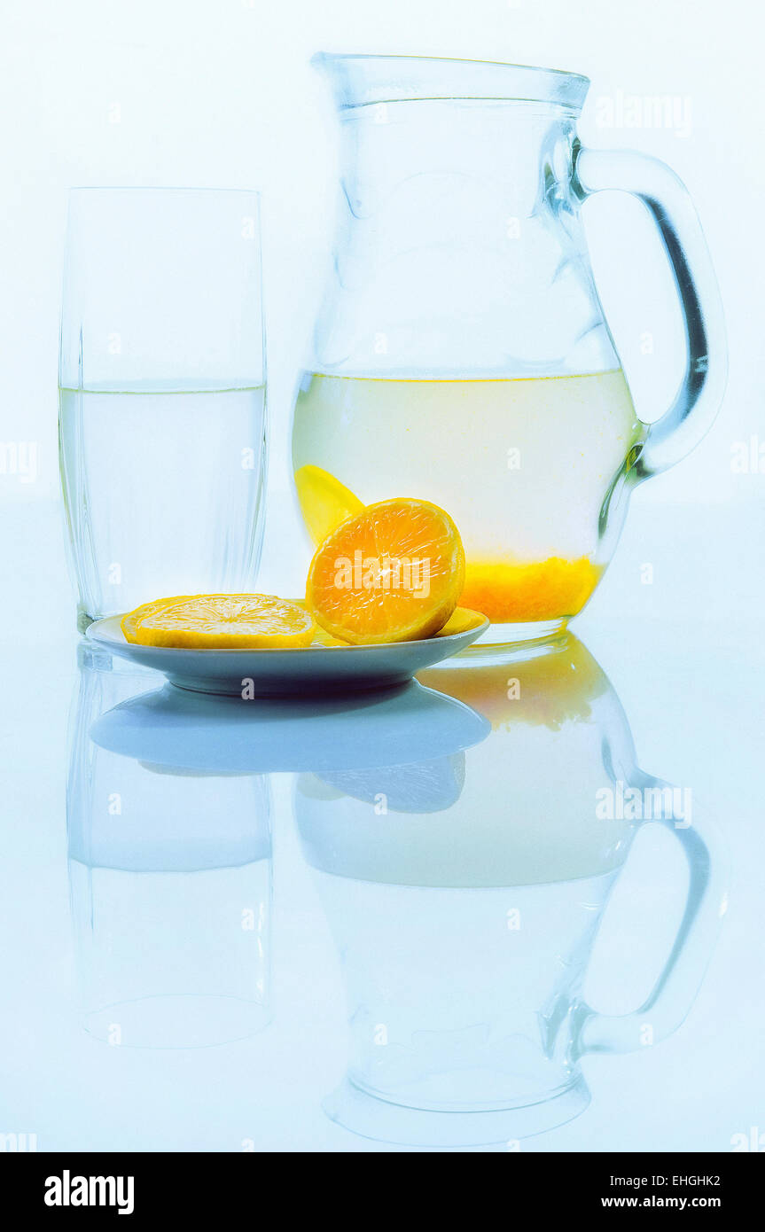 Krug mit Zitrone trinken in der Nähe von Glas mit einem Getränk und einen Teller mit Zitrone Stockfoto