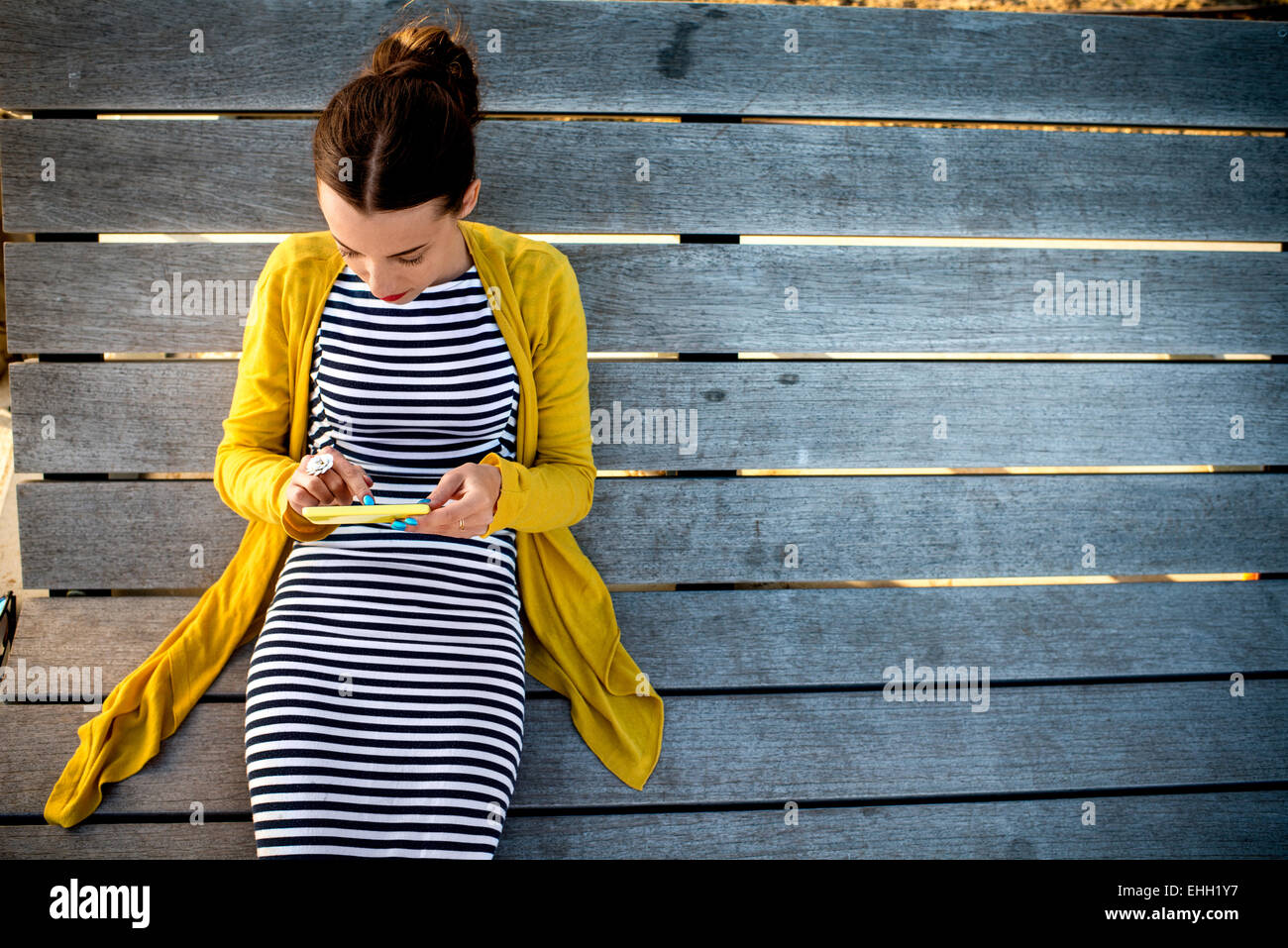 Frau mit Telefon auf Sonnenbank Stockfoto