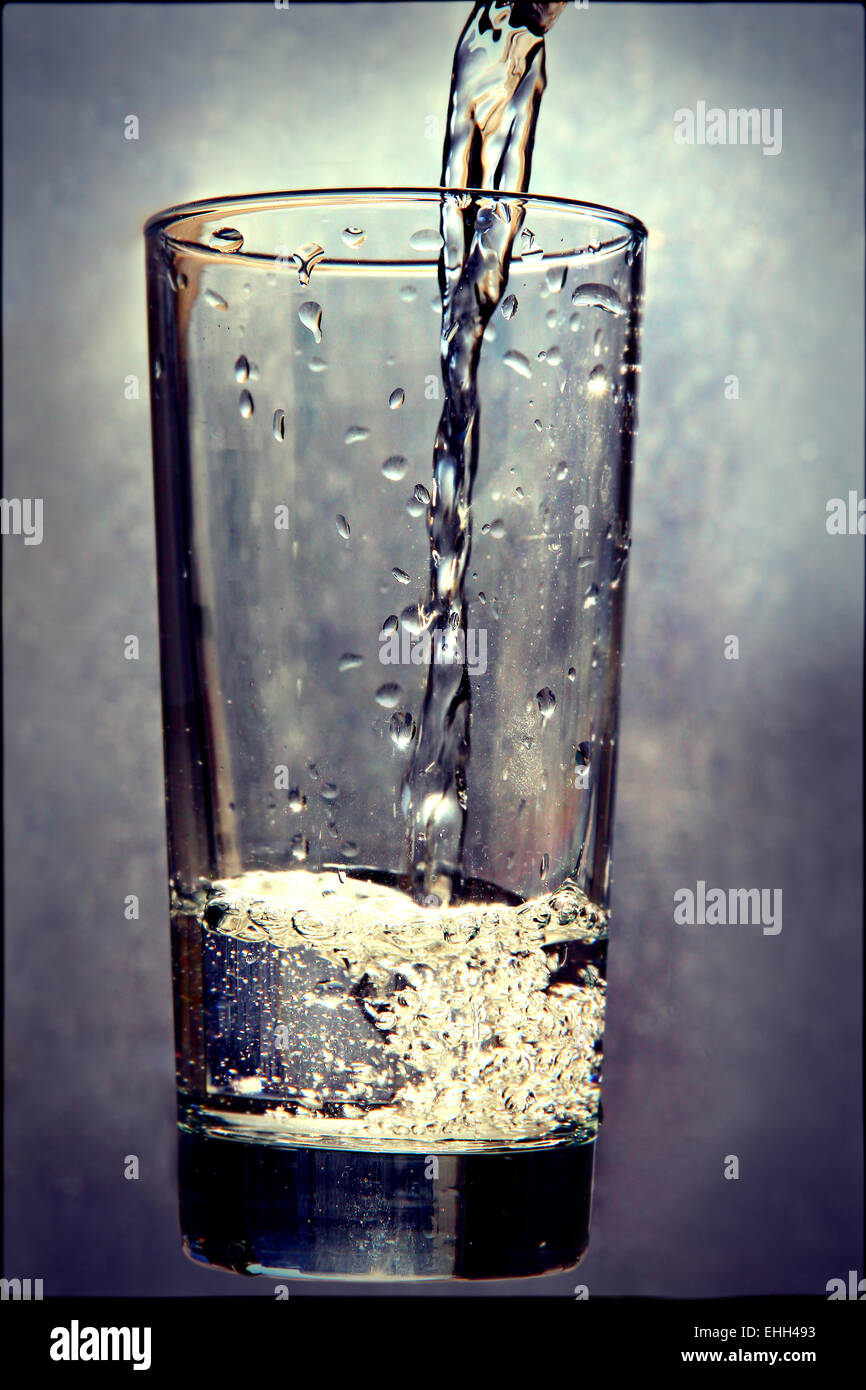 Flüssigkeit im Glas auf Grunge Hintergrund gießen. Durchtrainierten Bild. Stockfoto