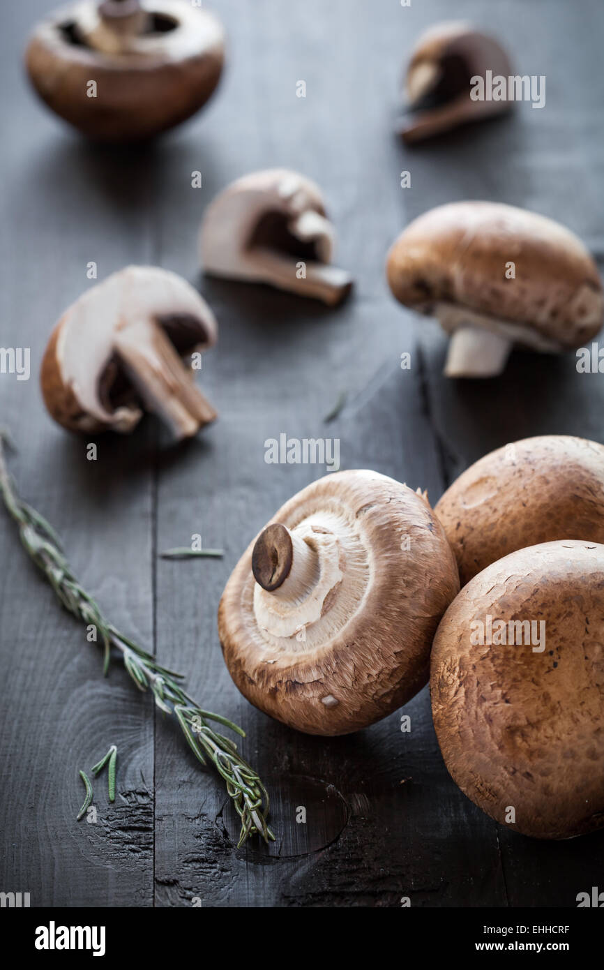 Frische leckere Portobello-Pilze dekoriert Rosmarin auf hölzernen Hintergrund Stockfoto