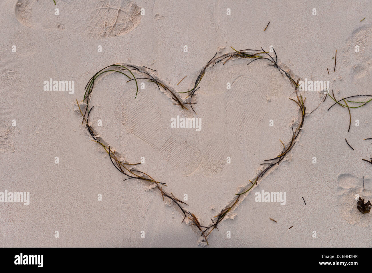 Herz durchbohrt von Amors Pfeil in den Sand gezeichnet Stockfoto