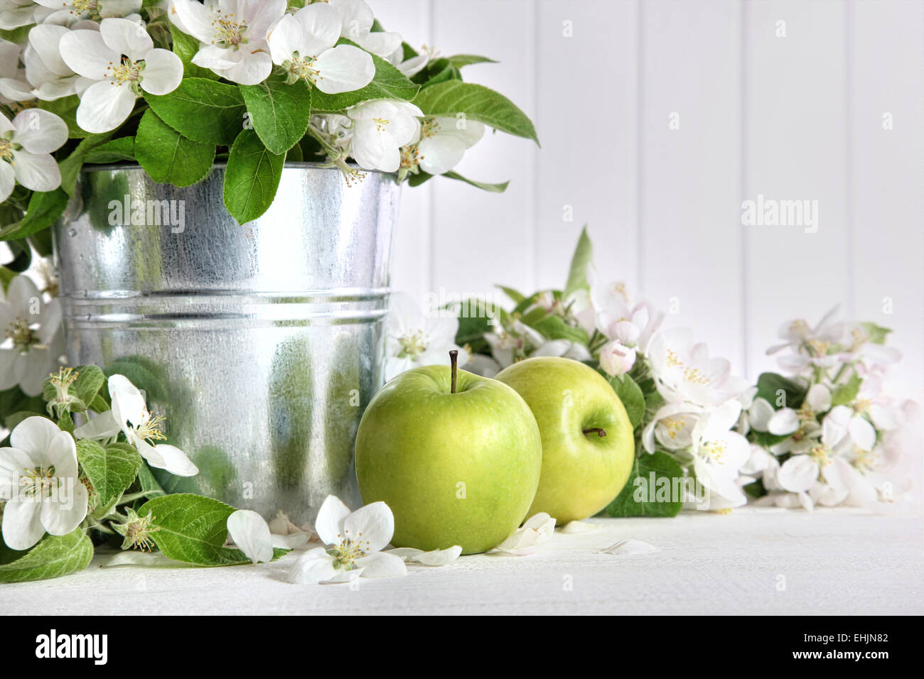 Grüne Äpfel mit Blüten auf Tisch Stockfoto