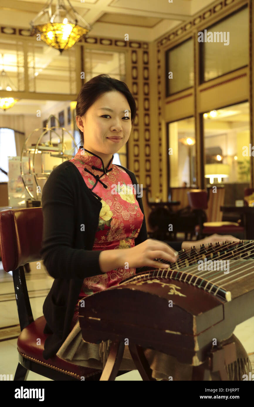 Frau spielt ein Guzheng ein traditioneller chinesischer Musik-Instrument in der Lobby des Fairmont Peace Hotel in Shanghai China Stockfoto