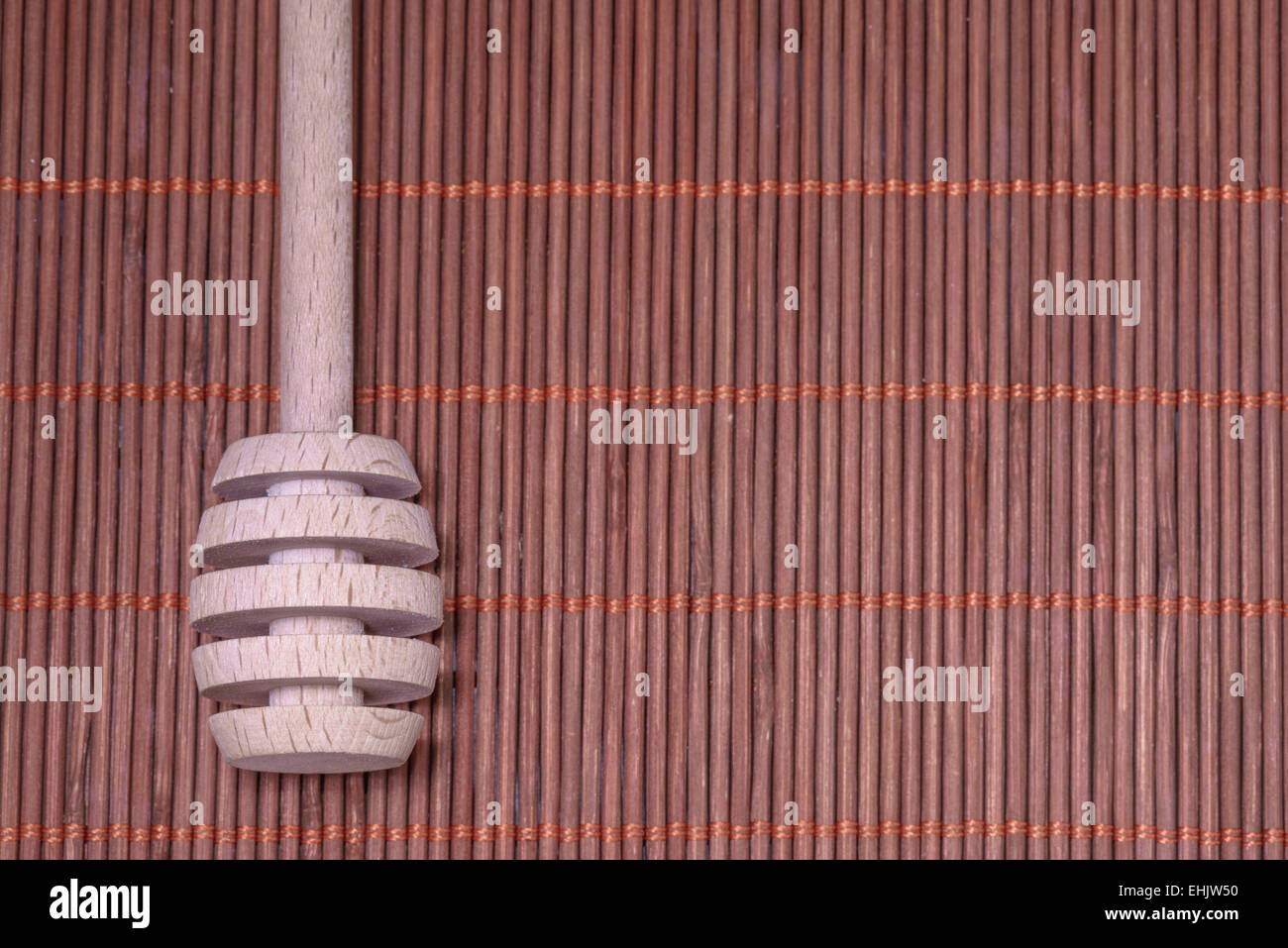 Holz-Honig-Löffel auf einem schönen geflochtenen Teppich als Hintergrund Stockfoto