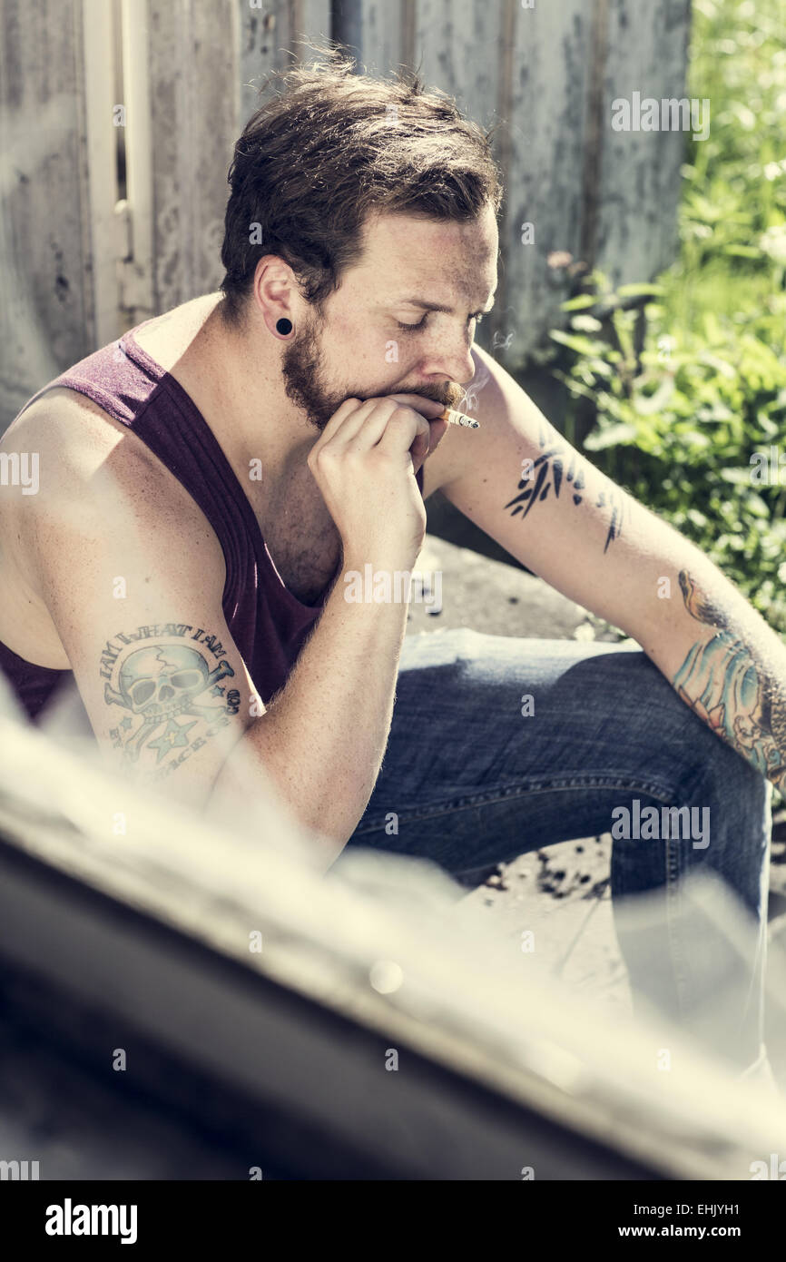 Ein Redneck draußen ein verlassenes Haus und Zigaretten rauchen. Stockfoto