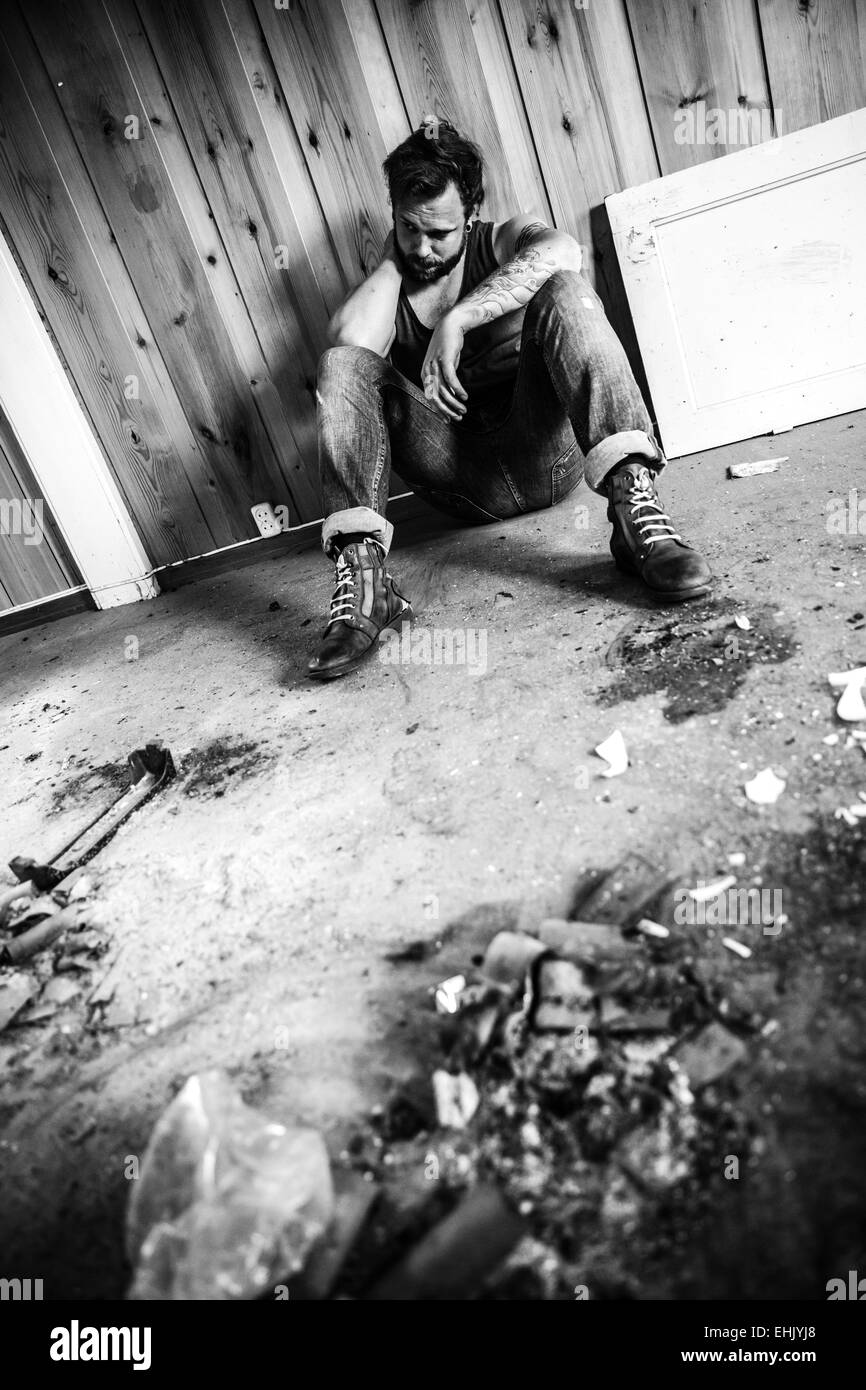 Punk Rocker oder Redneck sitzt auf dem Boden und chaotisch Haus denken. Stockfoto