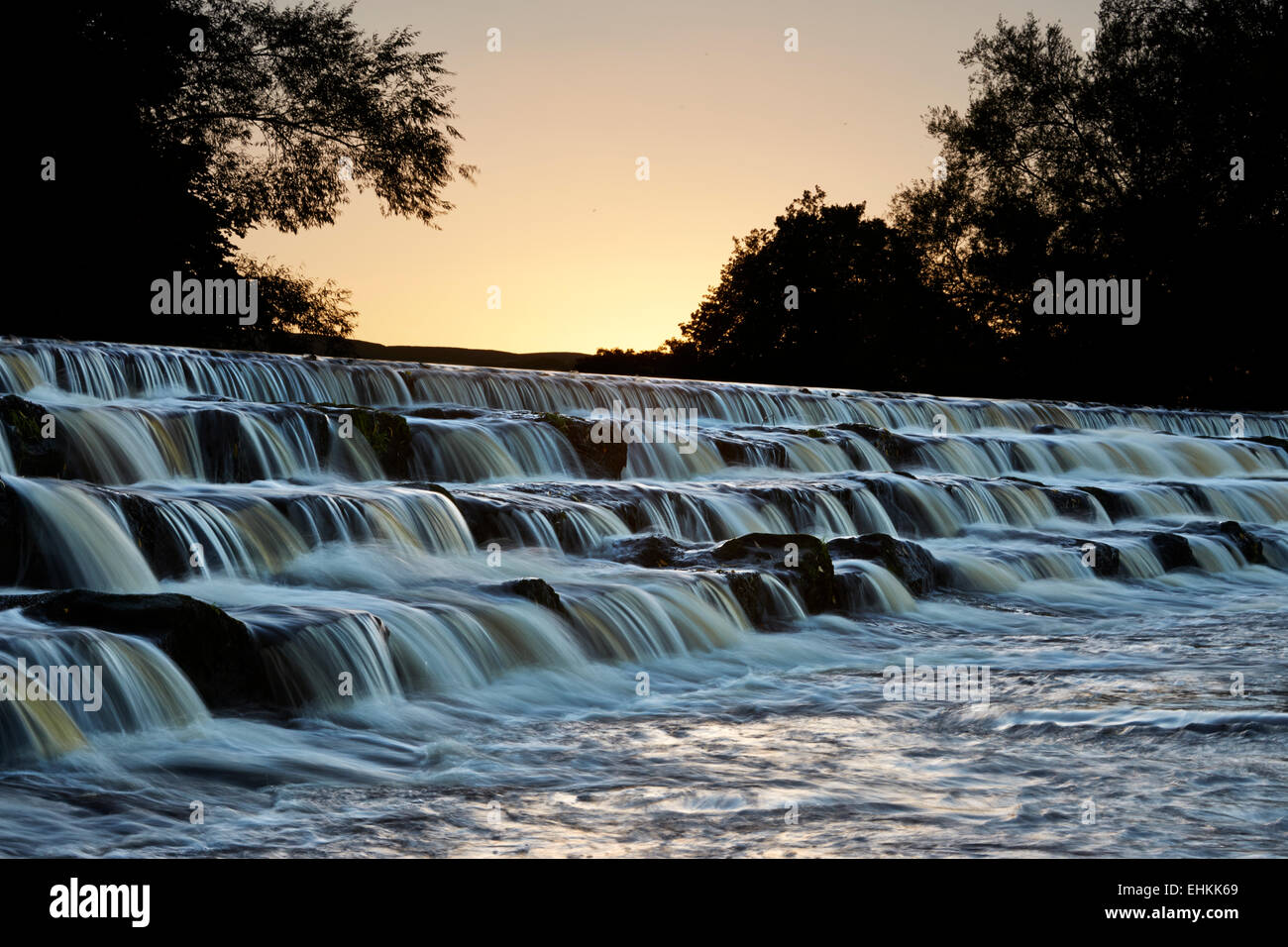 Sonnenuntergang über das Wehr am Fluß Wharfe im Burley in Wharfedale Stockfoto