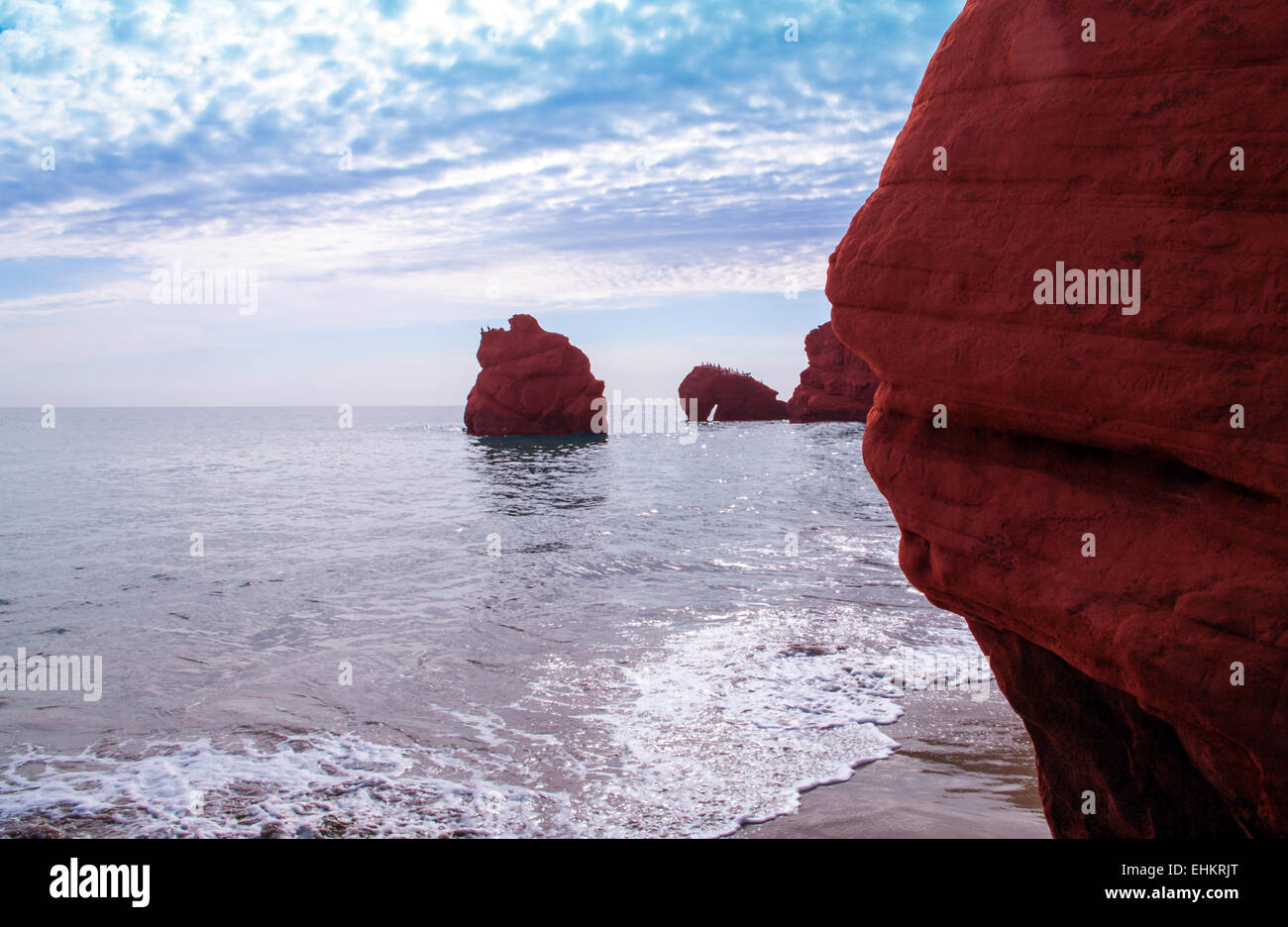Welle auf roten Klippen am Dune de Sud Stockfoto