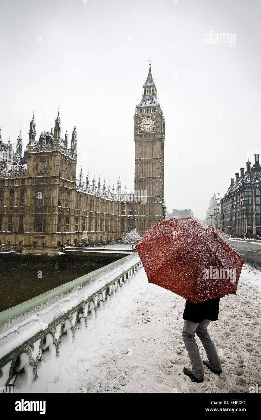 Ein Mann Unterstände unter einem Regenschirm in den Schnee, Westminster, London, Großbritannien Stockfoto
