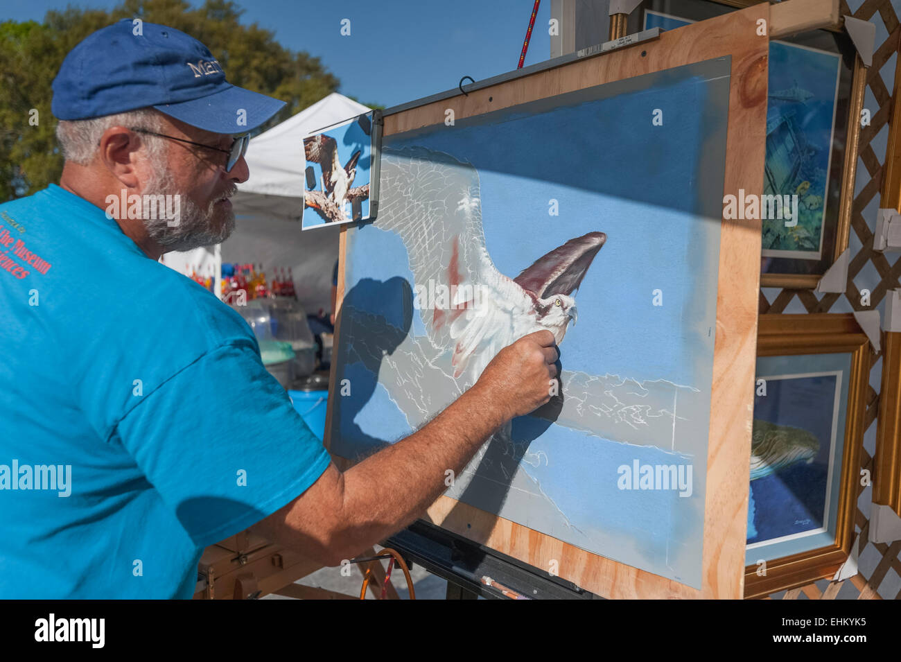 Ein Künstler mit Kreide auf einer Zeichnung auf einer Veranstaltung in Tavares, Florida setzt einen Stand für die Darstellung seiner Arbeit. Stockfoto