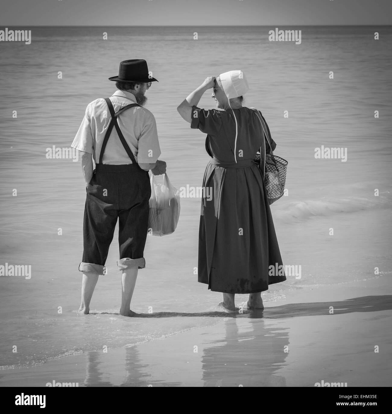 & Schwarz-weiß-Bild von Amish paar gekleidet in ihrer traditionellen Weise, genießen Sie die Brandung am Siesta Key Beach in Sarasota, FL Stockfoto