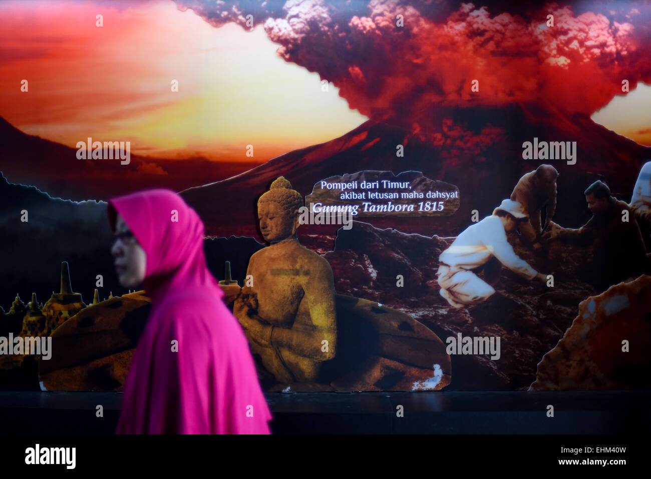 Frau geht durch bildliche Darstellung auf Mount Tambora und Borobudur-Tempel im Geologie Museum in Bandung. Stockfoto