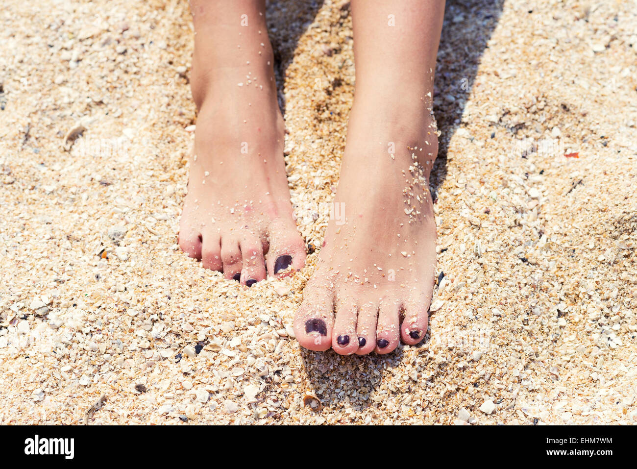 weibliche Füße mit Pediküre im Strandsand Stockfoto