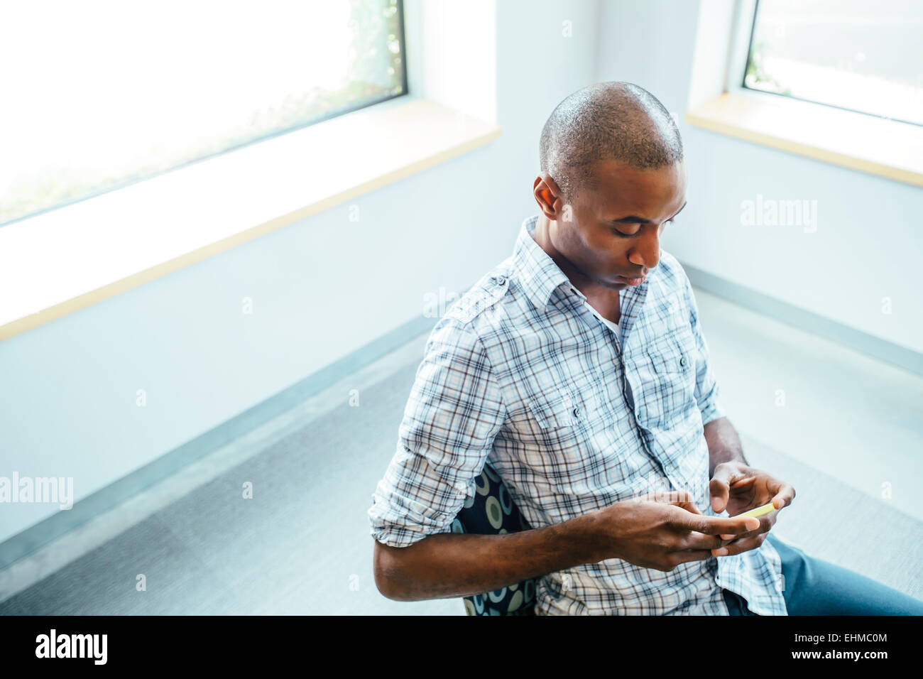 Schwarzer Mann mit Handy im Büro Stockfoto
