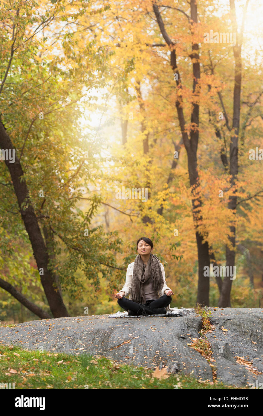 Asiatische Frau meditieren auf Felsen im park Stockfoto