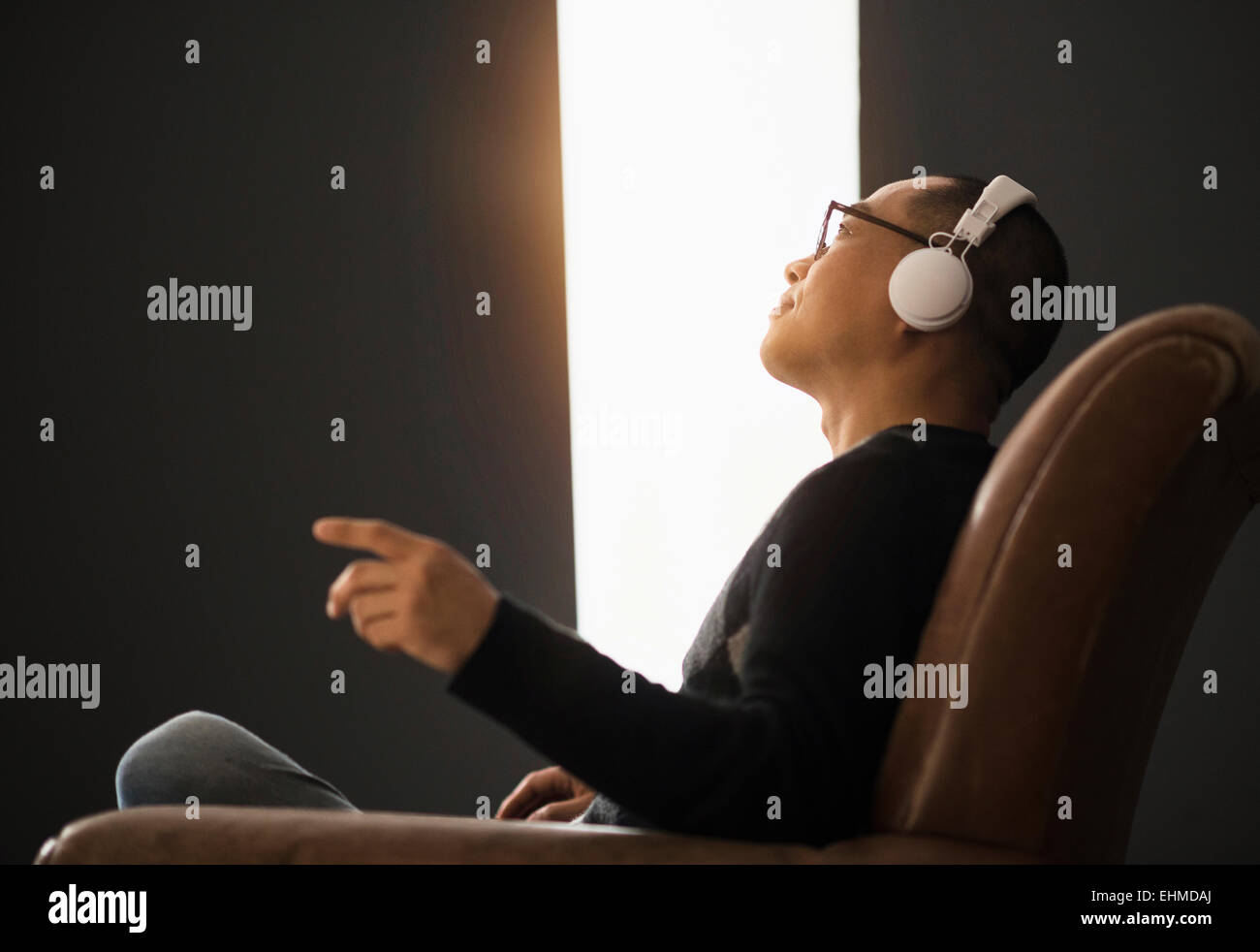 Koreanische Mann hören über Kopfhörer in Sessel Stockfoto