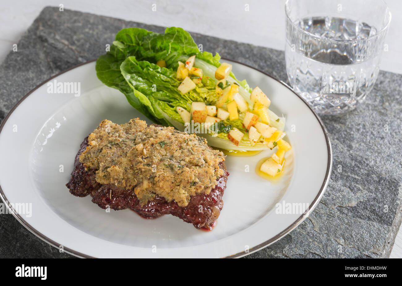 Rindersteak mit Senf-Kräuter-Kruste und Romaine Salatherzen mit Mango-Apfel-Vinaigrette. Stockfoto