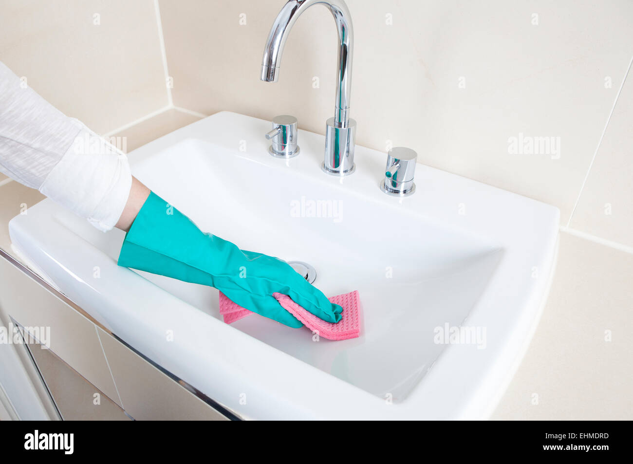 Hände mit Handschuhen eine Waschbecken mit einem Tuch zu reinigen Stockfoto