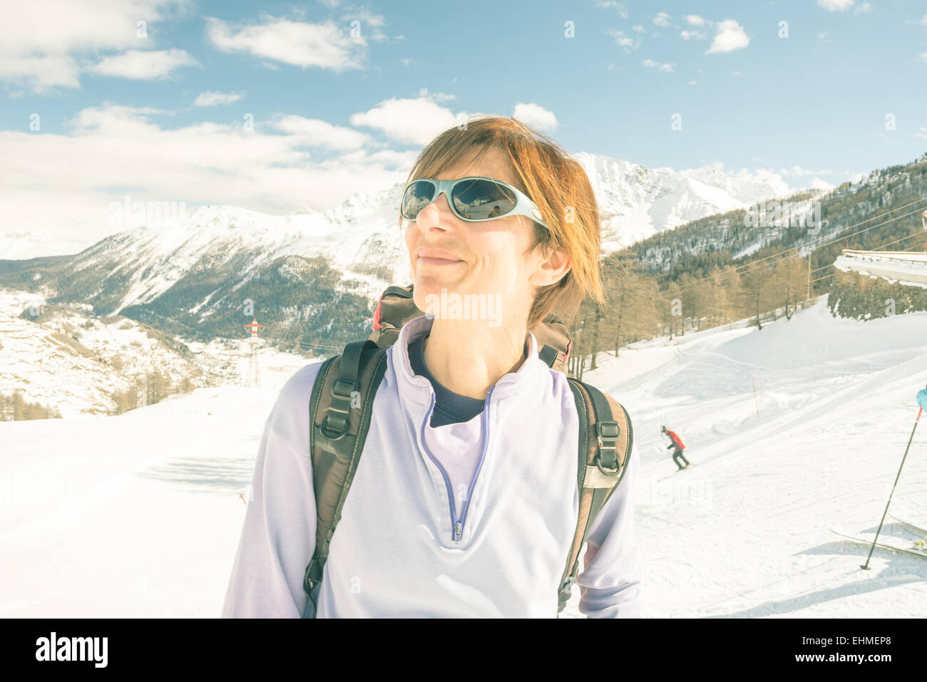 Erwachsene weibliche Skifahrer mit Rucksack und eine Sonnenbrille mit Glück an einem sonnigen Tag im Skigebiet von La Thuile, Aosta-Tal. Stockfoto