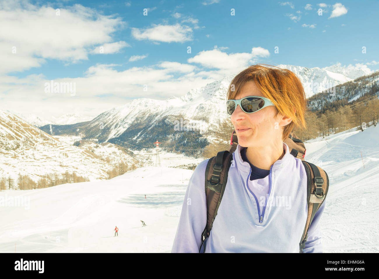 Erwachsene weibliche Skifahrer mit Rucksack und eine Sonnenbrille mit Glück an einem sonnigen Tag im Skigebiet von La Thuile, Aosta-Tal. Stockfoto
