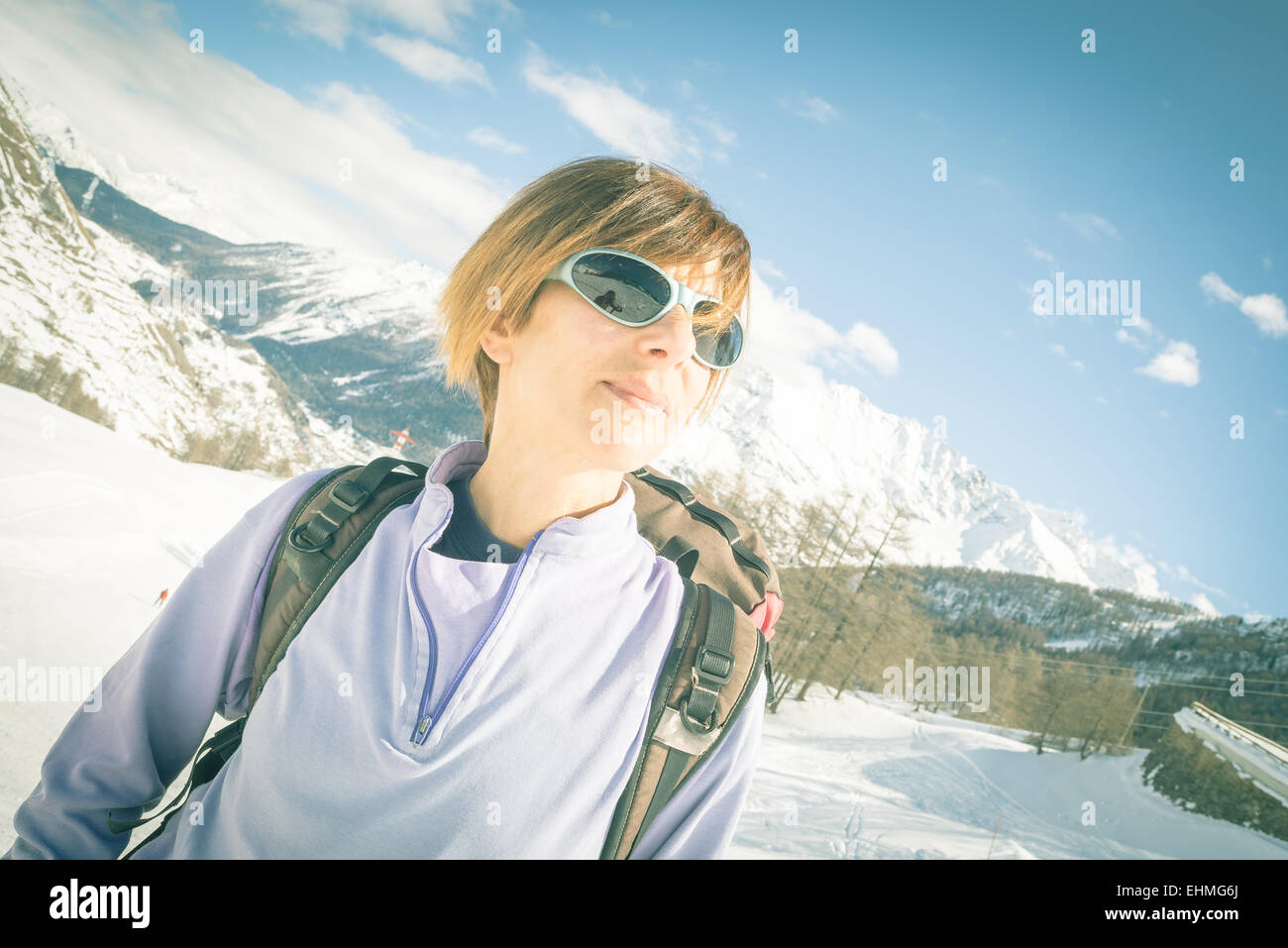 Erwachsene weibliche Skifahrer mit Rucksack und eine Sonnenbrille mit Glück an einem sonnigen Tag im Skigebiet von La Thuile, Aosta-Tal. C Stockfoto