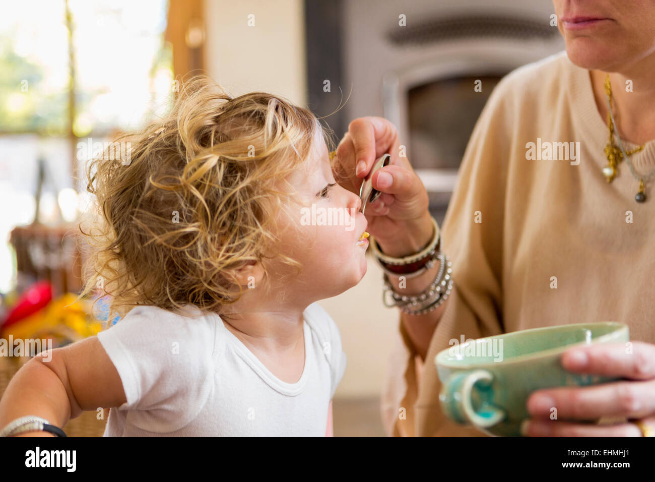 Kaukasische Mutter füttert Baby Sohn im Hochstuhl Stockfoto