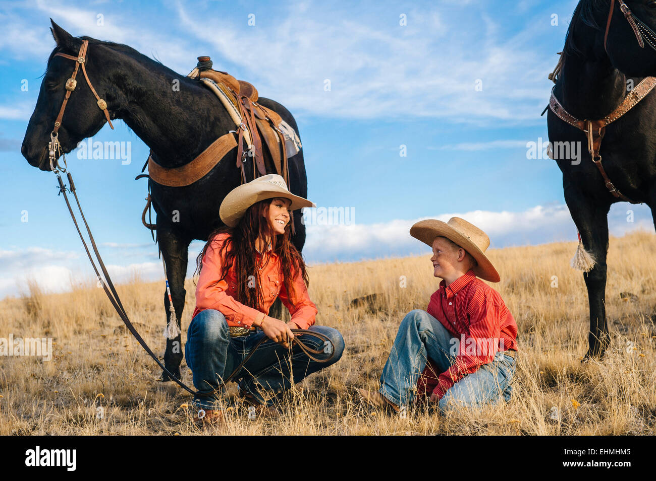 Kaukasische Mutter und Sohn mit Pferden in der Wiese Stockfoto