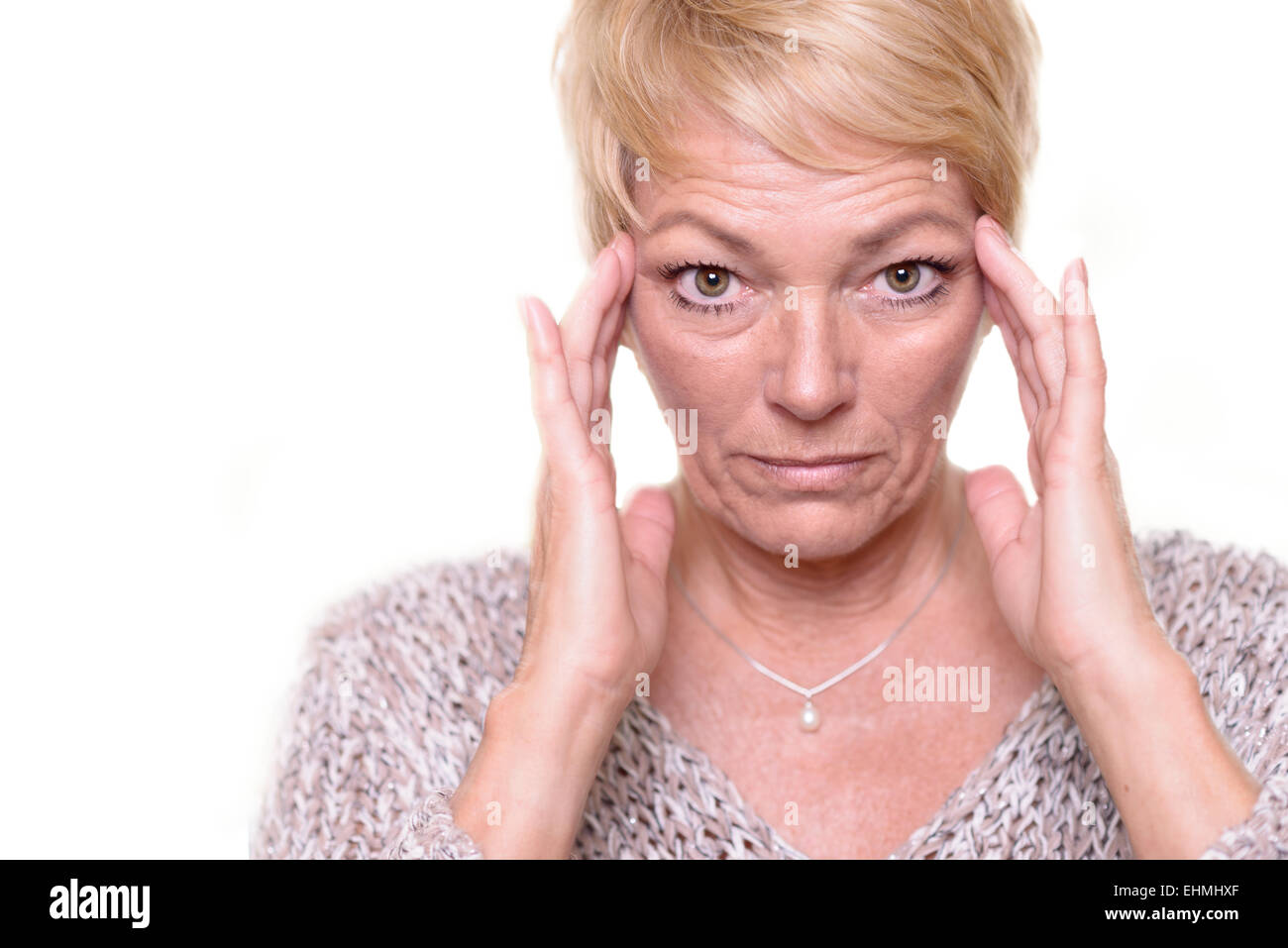 Attraktive ältere blonde Frau mit einem weit aufgerissenen Augen Ausdruck und ihre Brille auf dem Kopf, Kopfschmerzen oder Migräne angibt Stockfoto