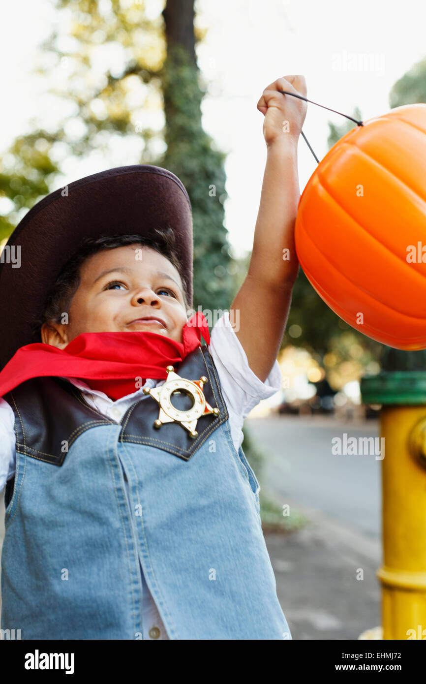 Gemischte Rassen junge verkleidet als Cowboy Halloween Kürbis Eimer halten Stockfoto