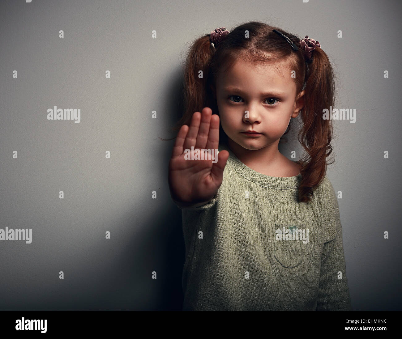 Angry Kid Girl zeigt Hand signalisiert, nützlich, um Kampagne gegen Gewalt und Schmerz auf dunklem Hintergrund zu stoppen. Closeup portrait Stockfoto