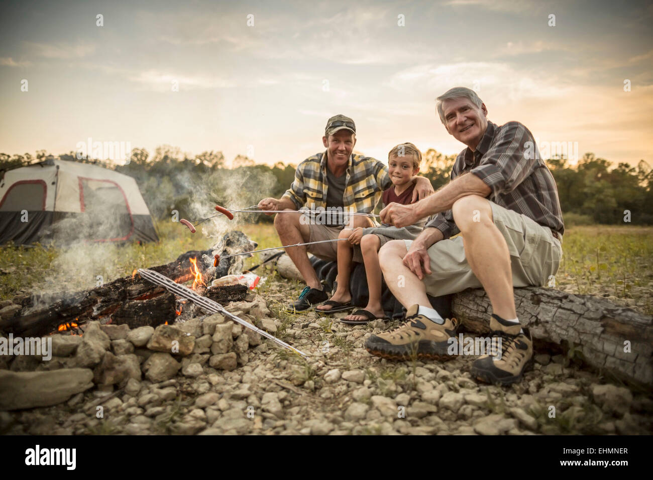 Drei Generationen von kaukasischen Männer Hotdogs über Lagerfeuer rösten Stockfoto