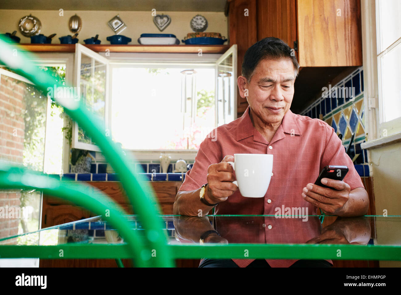 Philippinischen Mann mit Handy in Küche Stockfoto
