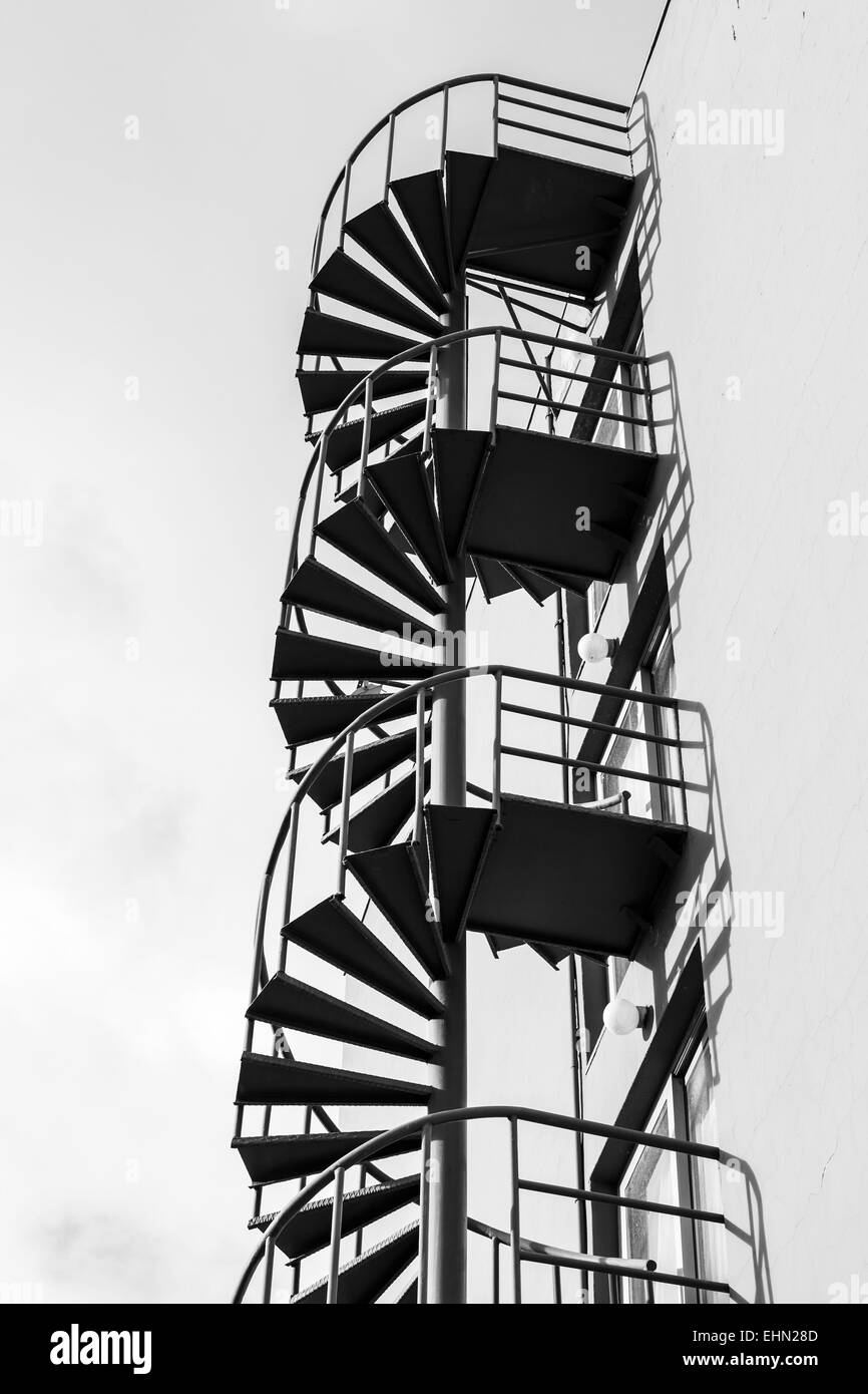 Abstrakt Architektur Fragment, alte Outdoor-Metall-Spirale-Leiter an der Wand, schwarz / weiß-Foto Stockfoto