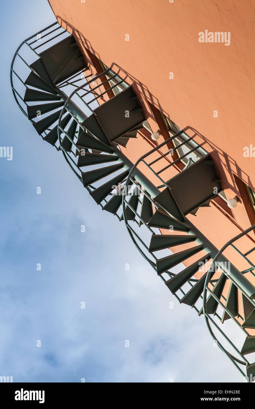 Abstrakt Architektur Fragment, alte Metallspirale Leiter an der roten Wand Stockfoto