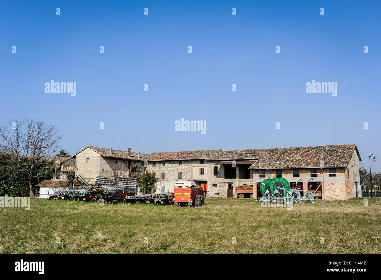 Sprinkleranlage mit Rohren und im Hintergrund ein Alter Bauernhof Stockfoto