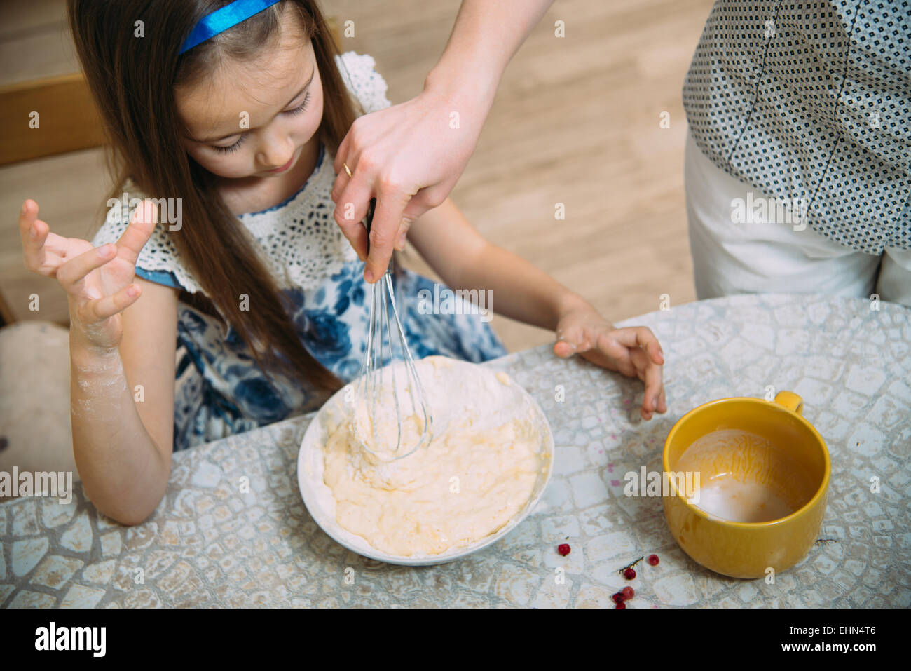 kleiner Helfer der Mütter. Kleine Mädchen den Teig für Pfannkuchen schlagen Stockfoto