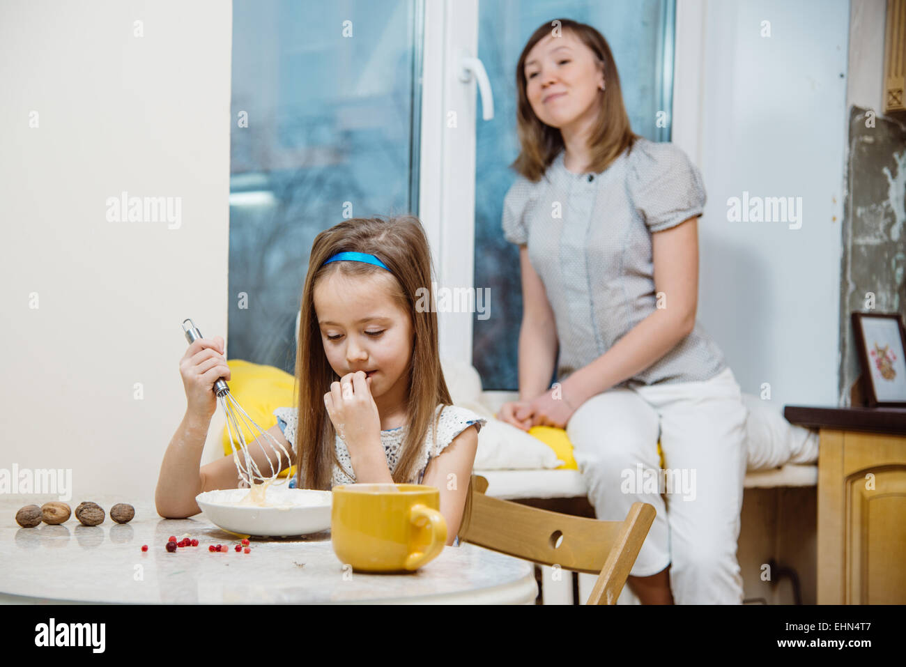 kleiner Helfer der Mütter. Kleine Mädchen den Teig für Pfannkuchen schlagen Stockfoto