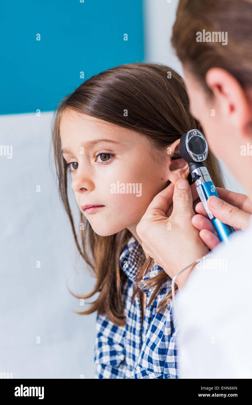 Arzt untersucht die Ohren von einem 7 Jahre alten Mädchen mit einem Otoskop. Stockfoto