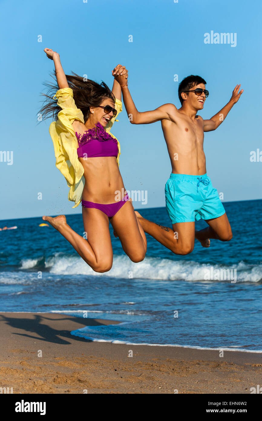 Dynamische Teen paar in Badesachen am Strand springen. Stockfoto