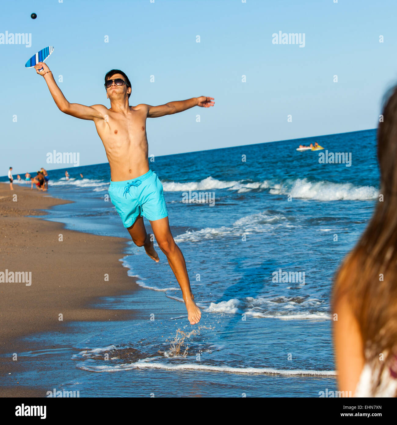 Junge Kugel-Beach-Tennis-Spieler springen auf Ball zu zerschlagen. Stockfoto