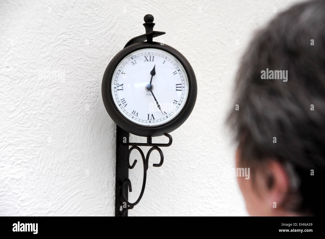 Alte Dame weiblichen Rentner Blick auf Uhr an Wand, die Zeit zu sagen Stockfoto