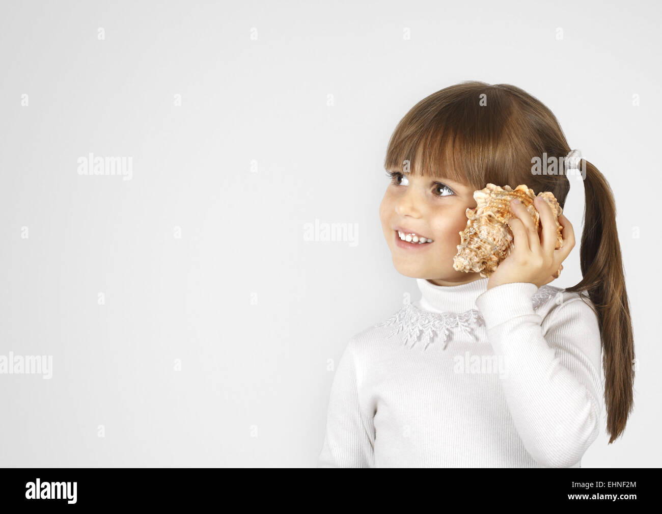 kleines Mädchen mit kleine Muschel Anruf simulieren Stockfoto