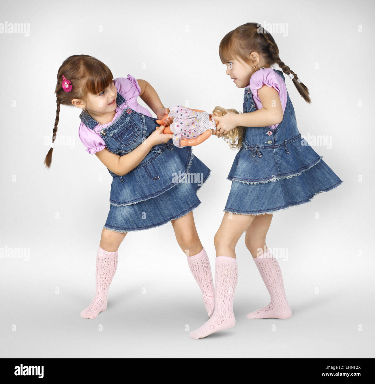 wenig twin Mädchen kämpfen und geteilt Puppe Stockfoto